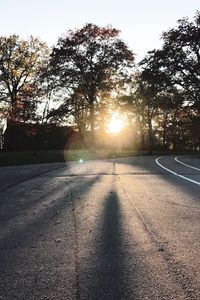 Road amidst trees against sky during sunset