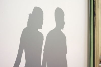 Silhouette couple standing against white wall