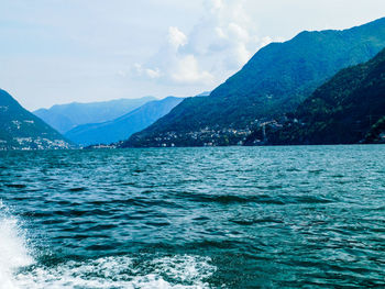 Scenic view of sea by mountains against sky