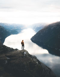 Rear view of man standing on rock against sky