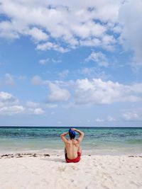 Full length of shirtless man relaxing on beach