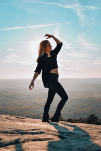 Full length of woman posing while standing on mountain against sky 