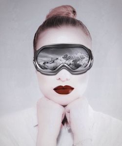 Close-up of woman wearing ski goggles against gray background