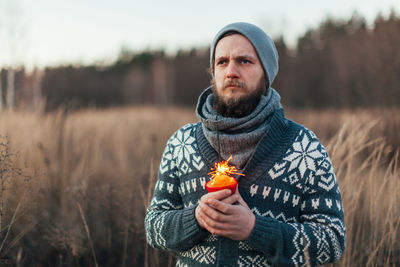 Close-up of young man holding sparkler while standing in forest