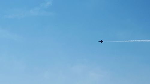 Low angle view of airplane flying against clear blue sky