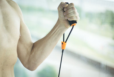 Shirtless man exercising by window