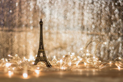 Close-up of small replica eiffel tower with illuminated string lights on table