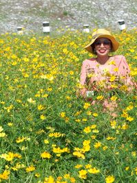 Portrait of smiling woman standing on yellow flowering plants