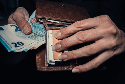 Cropped hand of woman holding purse with banknote