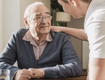 Young man taking care of grandfather at home