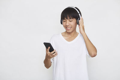 Young man using smart phone against white background