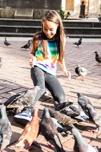 Girl feeding pigeons on city street