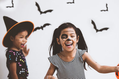 Cute playful girl with spooky make-up at home during halloween