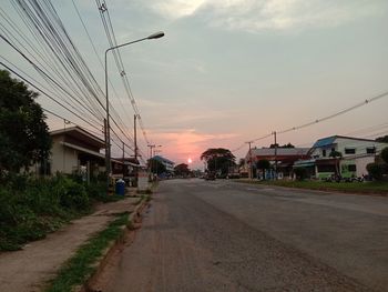 Street amidst buildings against sky during sunset