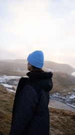 Rear view of woman looking at mountain against sky during sunset