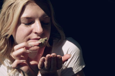 Close-up of woman smelling cannabis plant at home