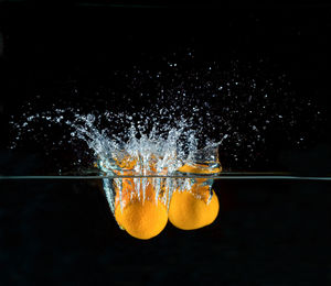 Close-up of water splashing on glass against black background