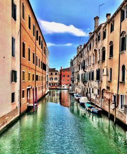 Canal amidst buildings in city against sky