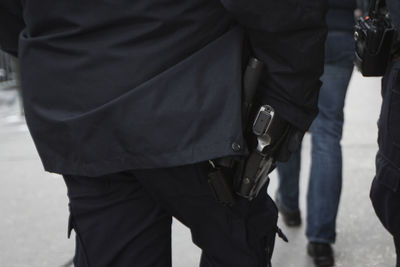 Midsection of men with gun walking on street