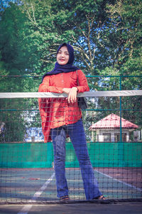 Full length portrait of woman standing against railing