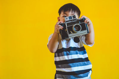 Portrait of man photographing against yellow background