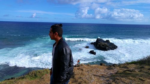 Side view of man standing on cliff by sea