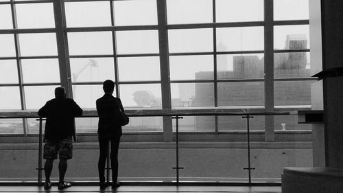 Rear view of people standing against window
