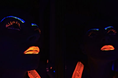 Reflection of woman with neon face paint on mirror