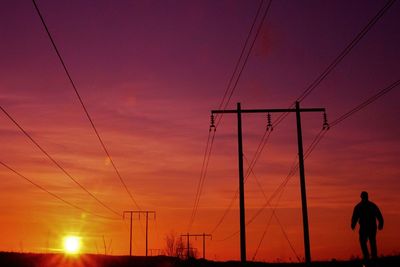 Silhouette of electricity pylon against sky during sunset