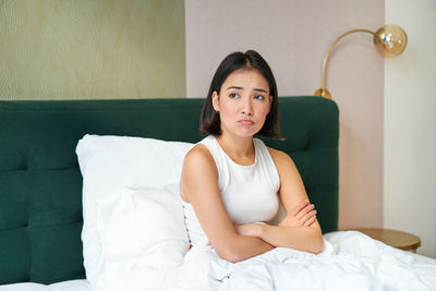 Portrait of woman sitting on bed at home