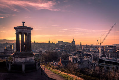 Sunset at dugald stewart monument with cityscape behind including edinburgh castle and north bridge