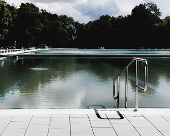 Swimming pool by lake against sky