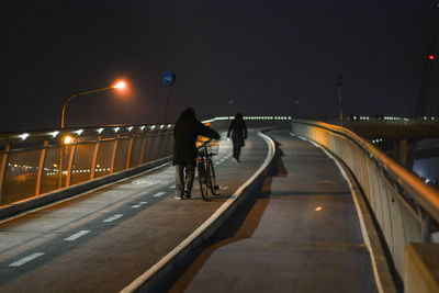 People on bridge against sky at night