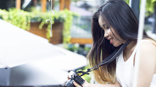 Young woman looking down while sitting outdoors