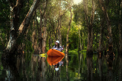 Asian traveler woman kayaking in mangrove forest of botanical garden, thailand. landscape travel 