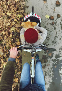 Low section of person holding bicycle on autumn leaves