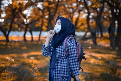 Rear view of woman standing by tree during autumn