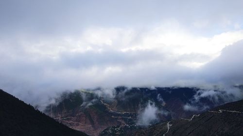 Scenic view of volcanic mountains against cloudy sky