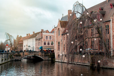 Arch bridge over river amidst buildings in city against sky