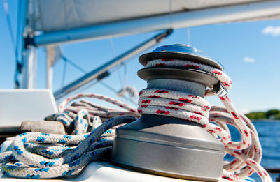 Close-up of roped rolled in bollard on sailboat against sky