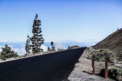 Road by building against clear blue sky