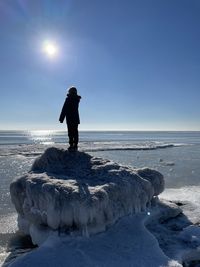 Full length of boy standing on ice covered land while looking at sea
