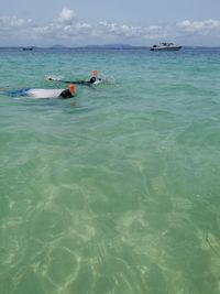 People swimming in sea against sky