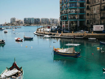 Boats moored in canal amidst buildings in city against sky