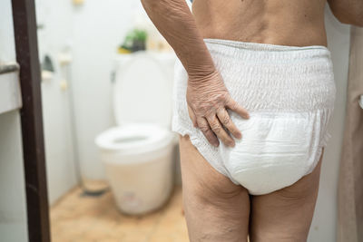 Midsection of senior woman wearing diaper in bathroom