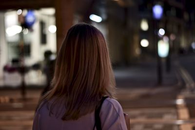 Rear view of woman standing in city at night