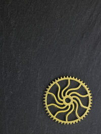 Close-up of golden gear on black table