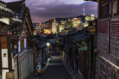 Road amidst houses in city during sunset