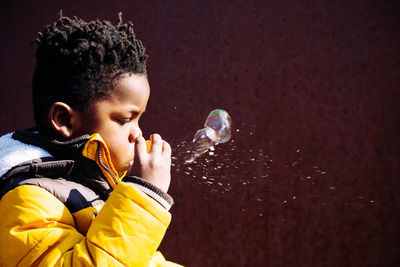 Side view of boy blowing bubbles