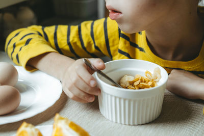 Boy eats breakfast in the morning with cereals with milk. flakes close-up